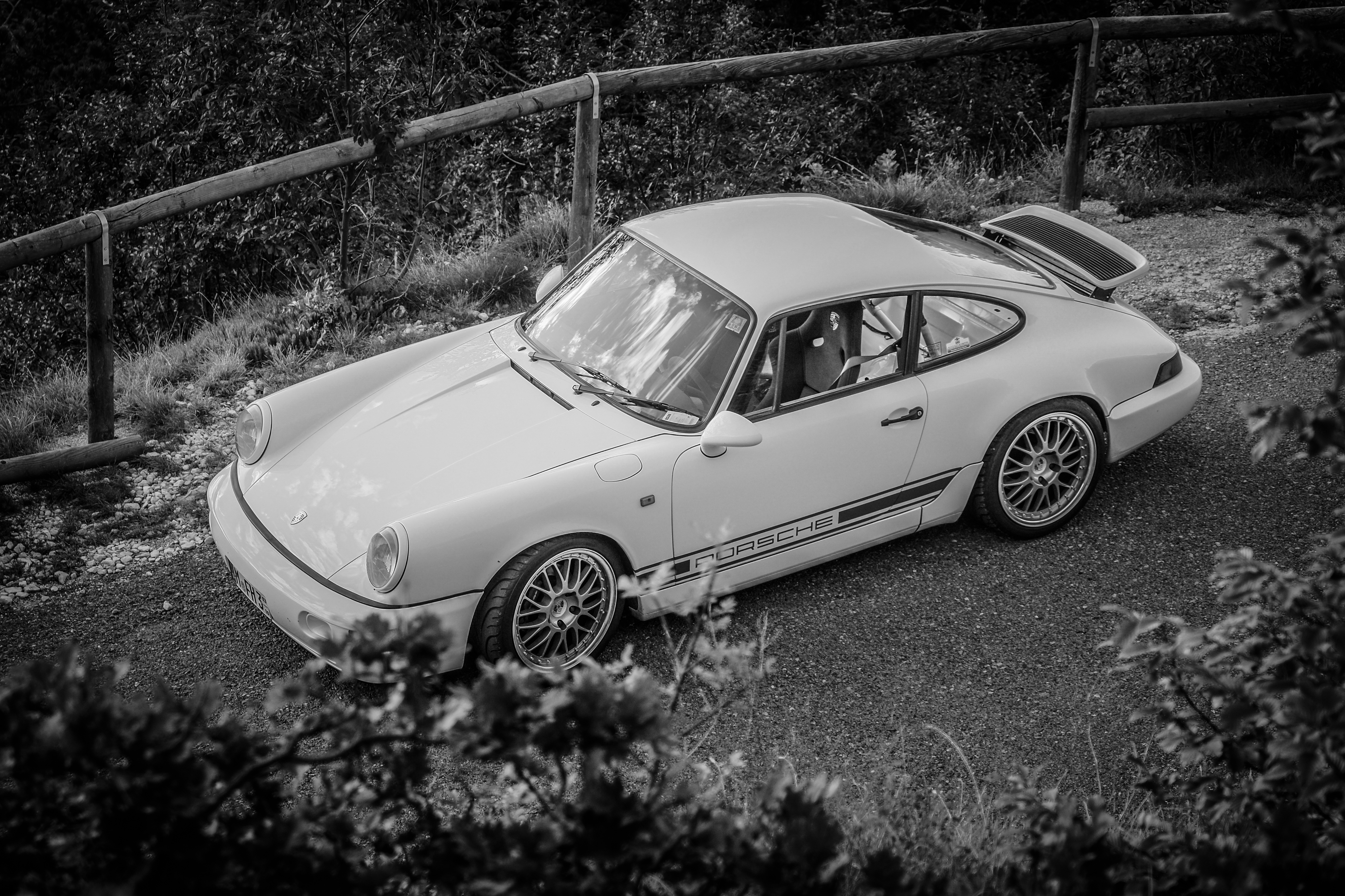 Weißer Porsche 964 von oben auf einem Waldweg, Schwarz-Weiß-Aufnahme