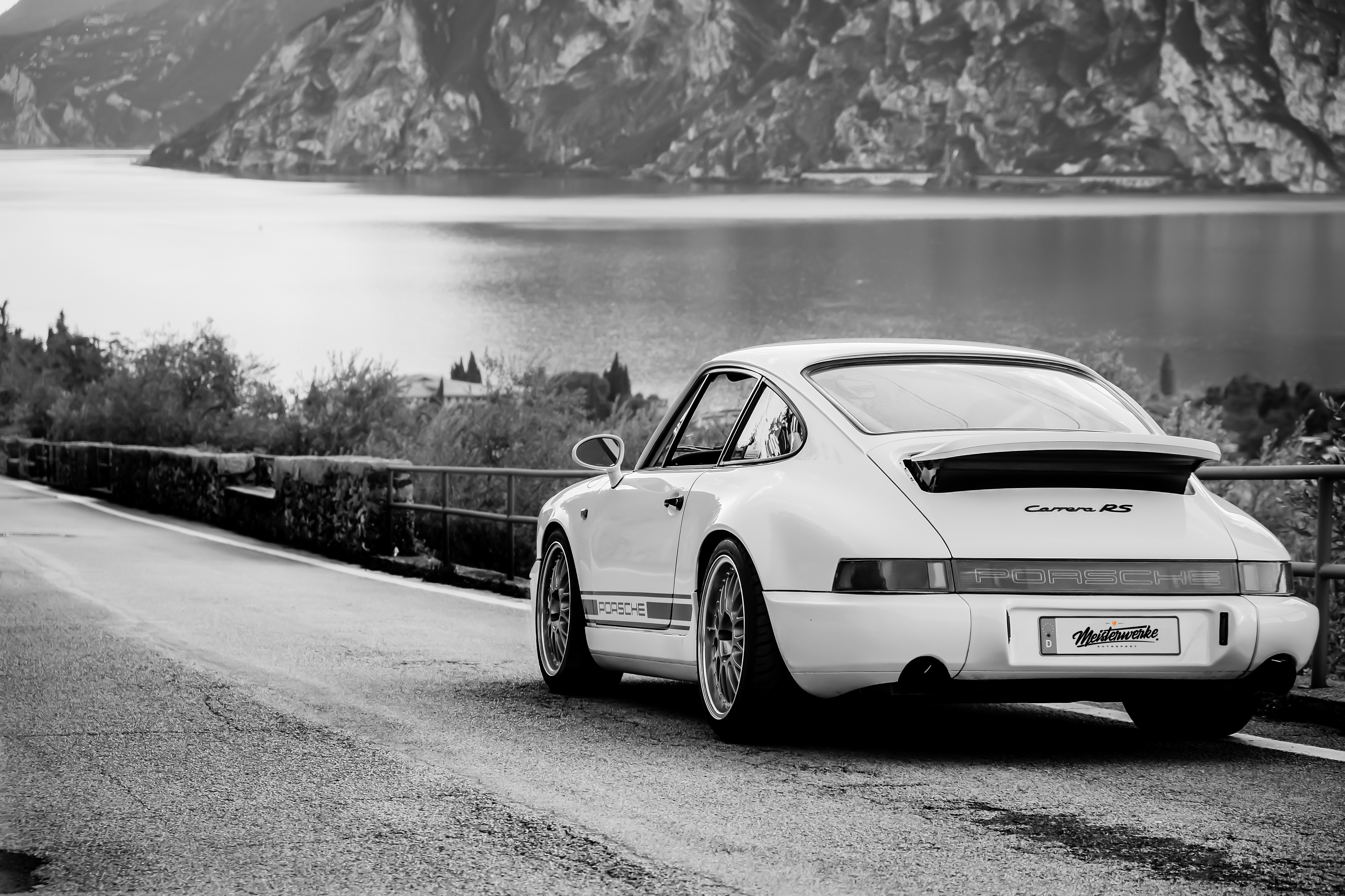 Weißer Porsche 964 an einer Uferstraße am See, Schwarz-Weiß-Aufnahme